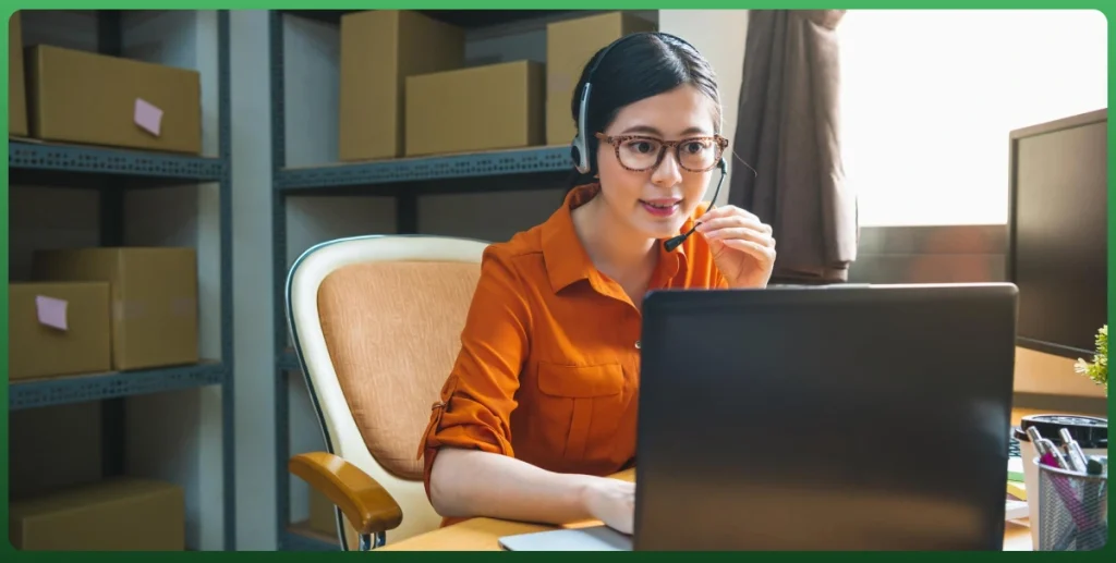 Customer support representative assisting an online shopper through a headset while managing ecommerce orders from a warehouse office.